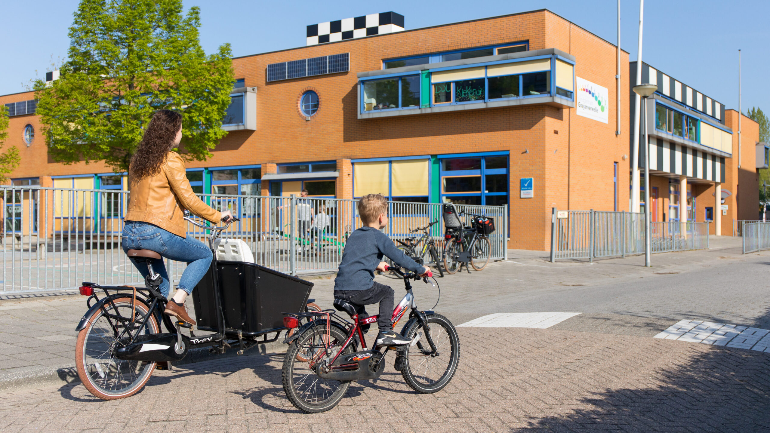 Foto van vrouw en kind die naar school fietsen.