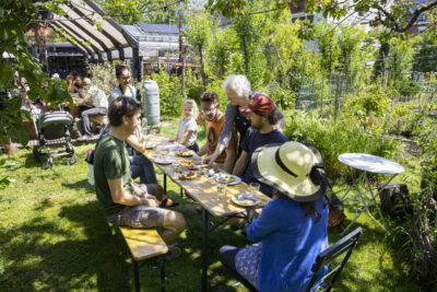 Bewoners Rotterdam zittend aan tafel in StadsOase de Spinozahof