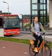 Een persoon fietst op een fietspad langs een bus