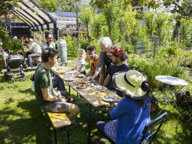 Bewoners Rotterdam zittend aan tafel in StadsOase de Spinozahof